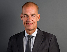 Carsten Cramer – Managing Director – in a dark suit with a dark tie looks straight at the camera (photo)