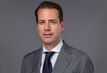 Lars Ricken – Managing Director – in a dark suit with a dark tie looks straight at the camera (photo)