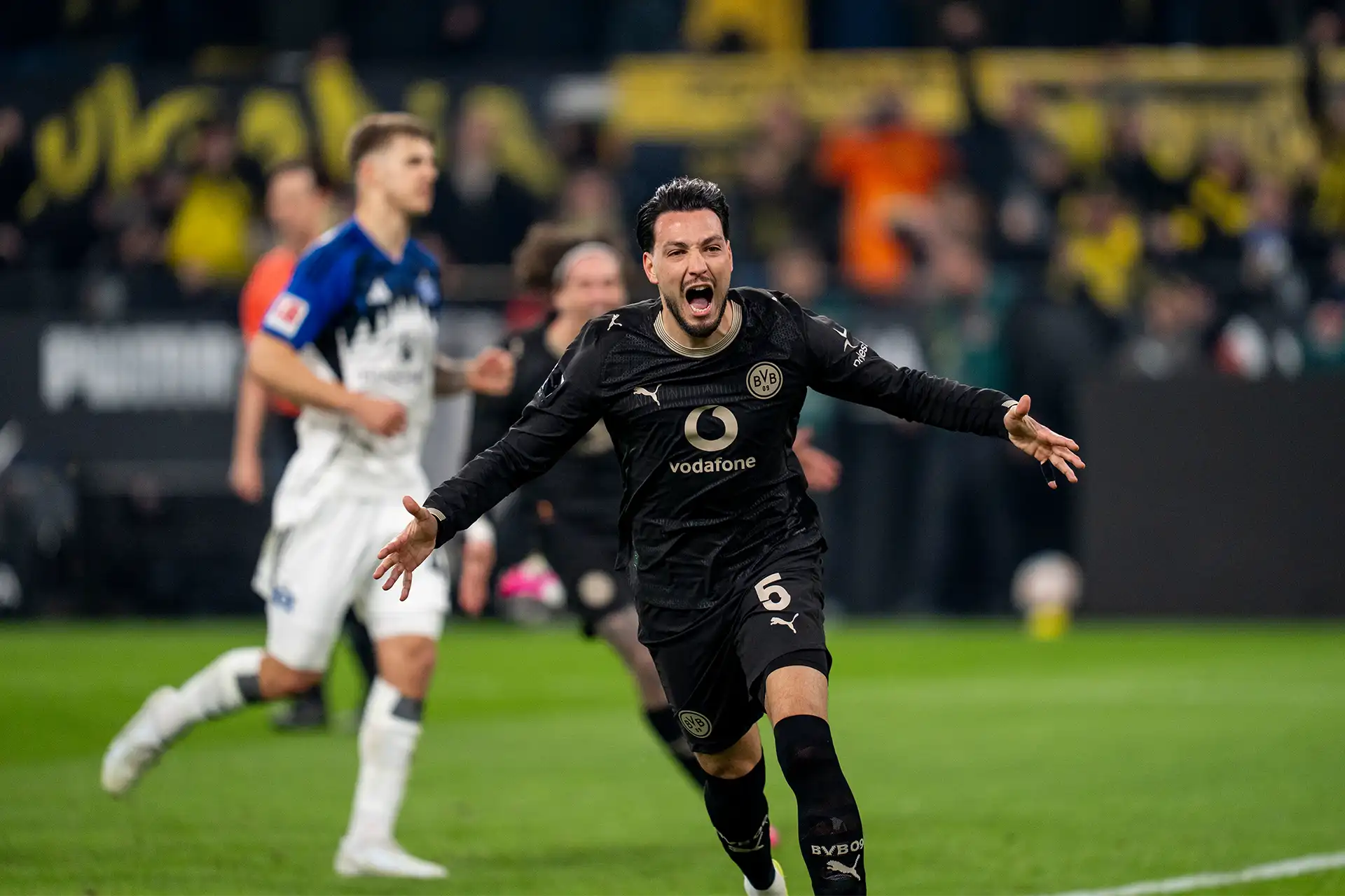 Bensebaini running away in celebration, an HSV player in the background (photo)