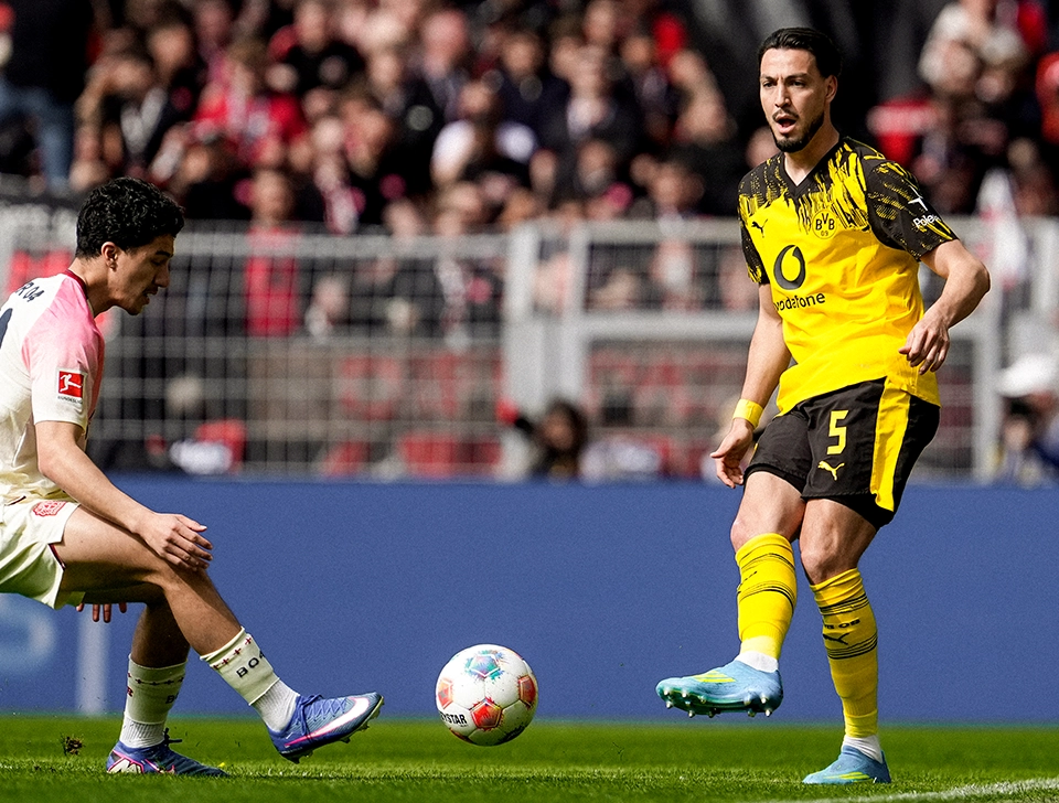 Bensebaini playing a pass near the touchline, a Leverkusen player trying to intercept the ball (photo)